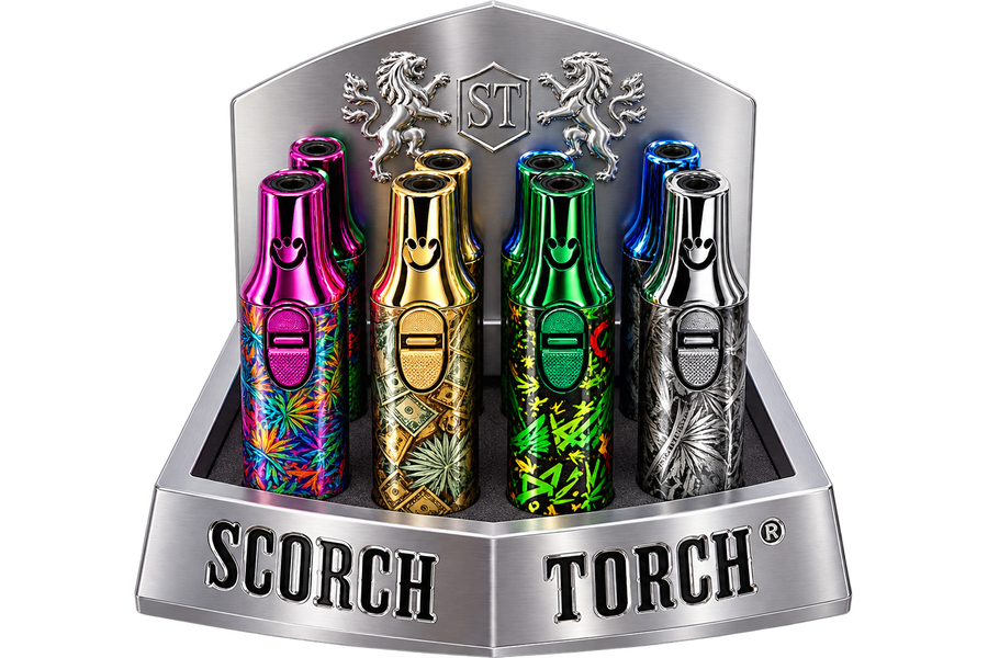 Four metallic disposable vape devices displayed in a silver branded retail stand. The devices feature colorful patterns and metallic finishes in pink, gold, green, and silver, with the SCORCH TORCH branding visible on the stand.